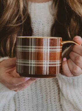 Tasse en porcelaine à carreaux, motifs tartan et poignée dorée.